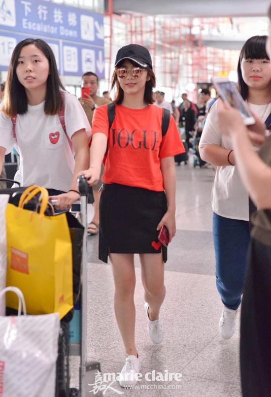 谭松韵机场街拍。她戴白色印字的黑色鸭舌帽和镜面墨镜,身穿黑色Vogue印字的红色T恤,下穿红色桃心印花的黑色短裙,脚踩白色球鞋,肩背黑色双肩包
