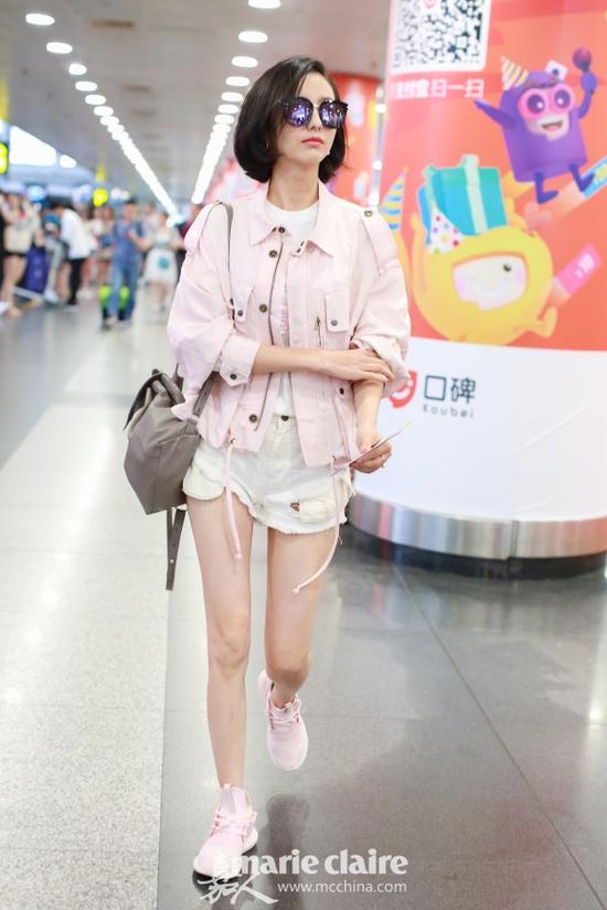 佟丽娅机场街拍。她戴紫色镜面墨镜,身穿粉色绑带夹克,内搭粉色亮片嘴唇装饰T恤,肩背Longchamp灰色双肩包,下穿白色破洞毛边牛仔短裤,脚踩Adidas粉色运动鞋。
