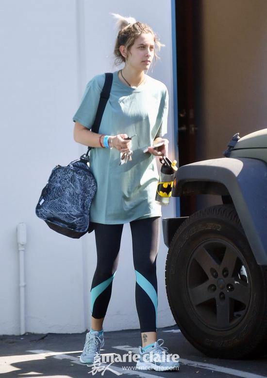 帕丽斯·杰克逊(Paris Jackson)时尚街拍。她身穿豆沙绿T恤,下穿黑色蓝色拼色运动Legging,脚踩灰色球鞋,肩背黑白印花的旅行袋。